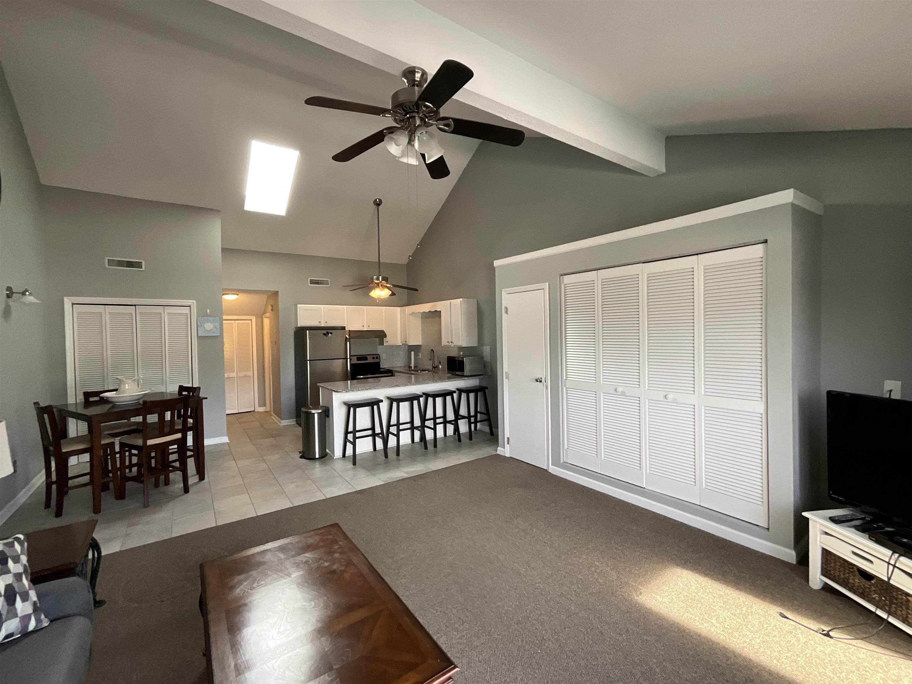 1880 Colony Drive, Unit 11O Surfside Beach, SC 29575 - Photo 2 of 17 Living room with high vaulted ceiling, a ceiling fan, beam ceiling, light colored carpet, and light tile patterned floors