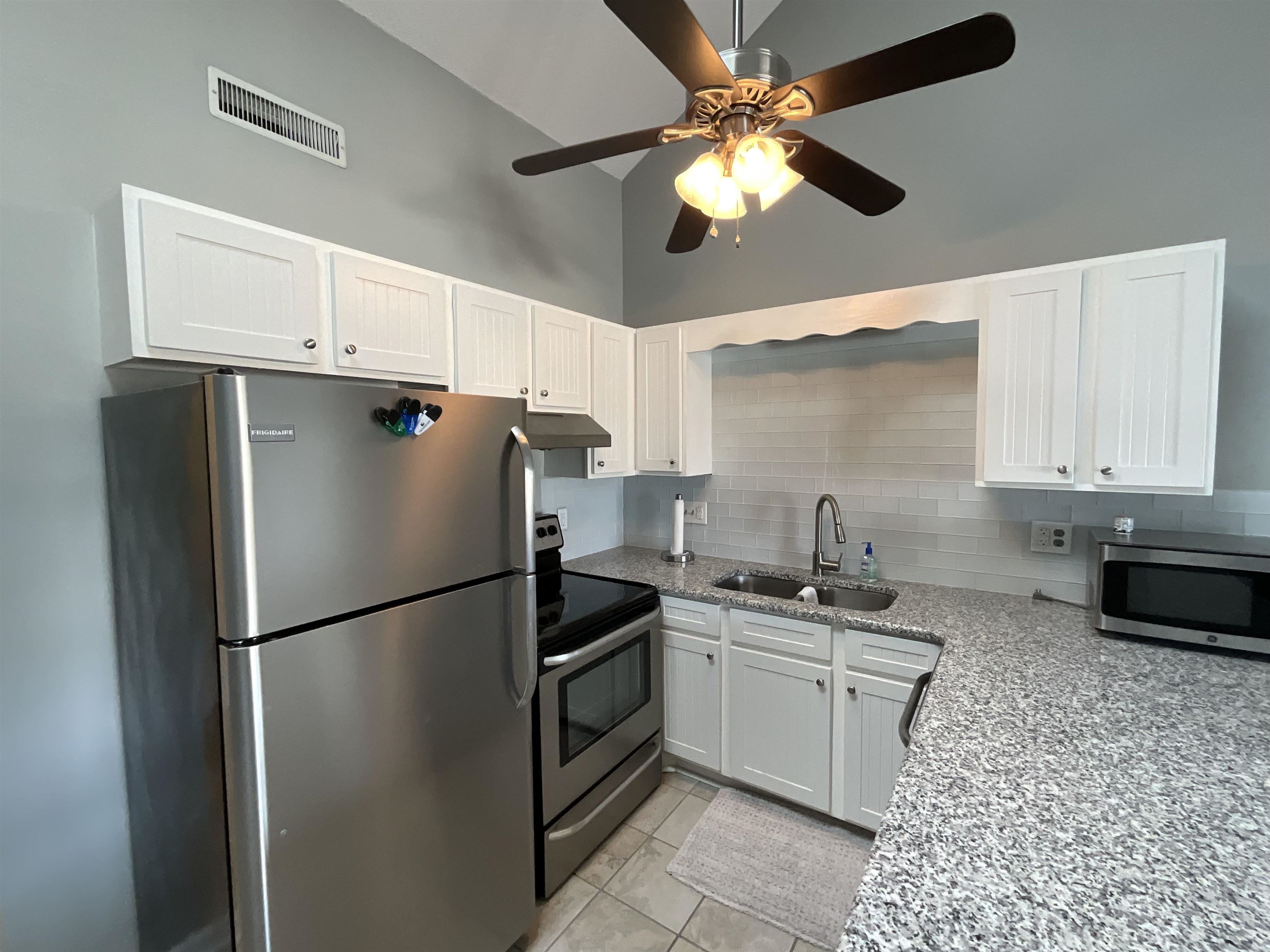 1880 Colony Drive, Unit 11O Surfside Beach, SC 29575 - Photo 2 of 14 Kitchen featuring light stone countertops, stainless steel appliances, white cabinetry, light tile patterned floors, and decorative backsplash