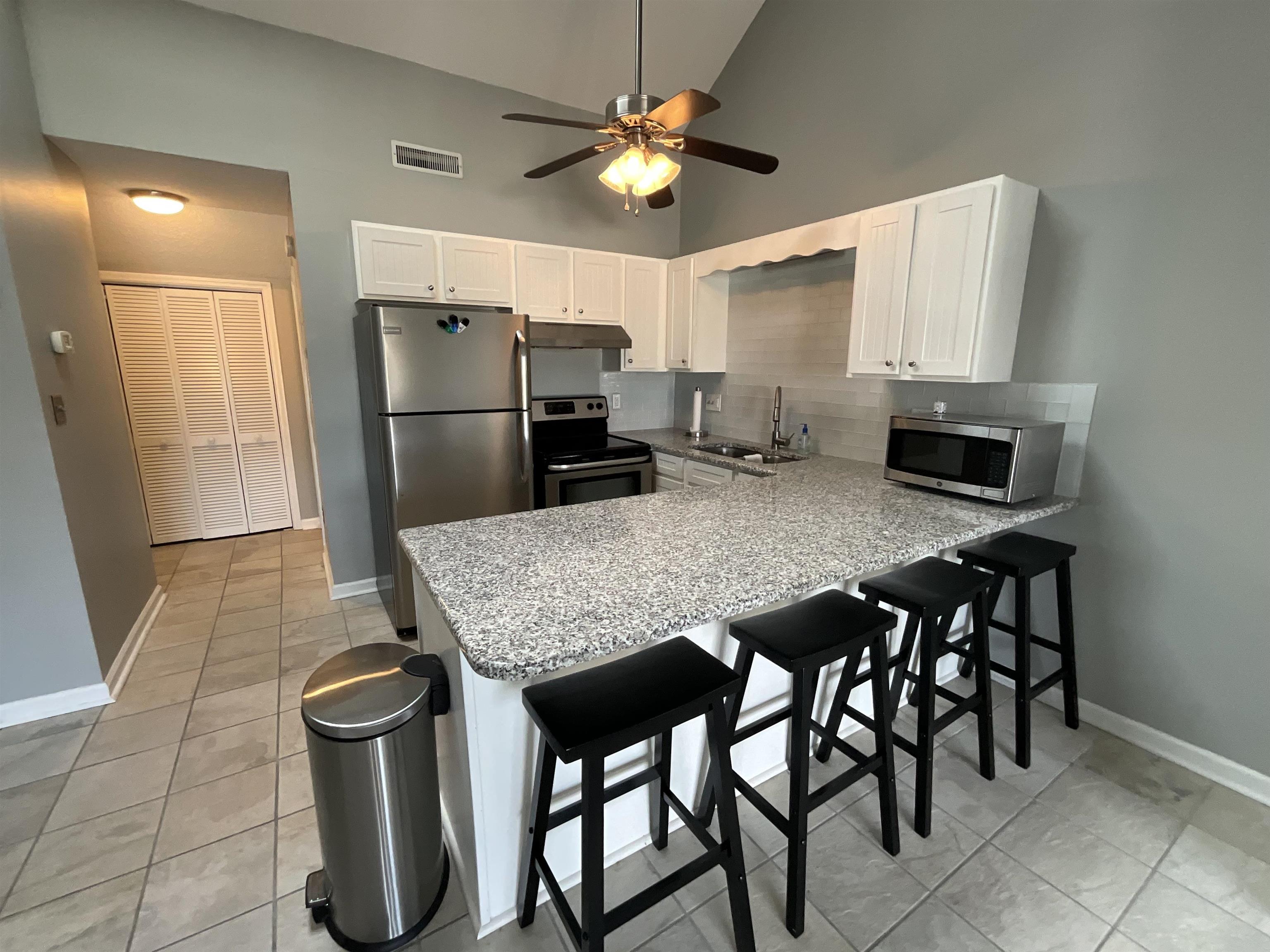 1880 Colony Drive, Unit 11O Surfside Beach, SC 29575 - Photo 4 of 17 Kitchen featuring white cabinets, stainless steel appliances, high vaulted ceiling, a breakfast bar area, and a peninsula