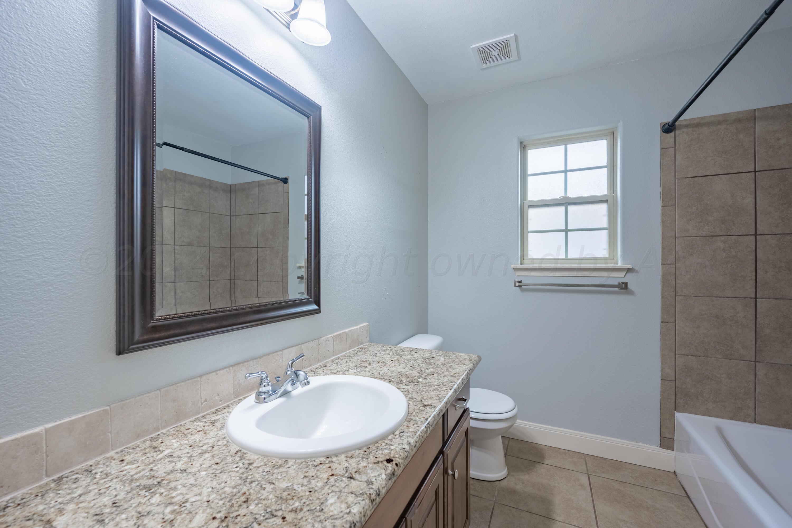 4512 Ross Street Amarillo, TX 79118 - Photo 11 of 24 a bathroom with a granite countertop sink toilet and shower