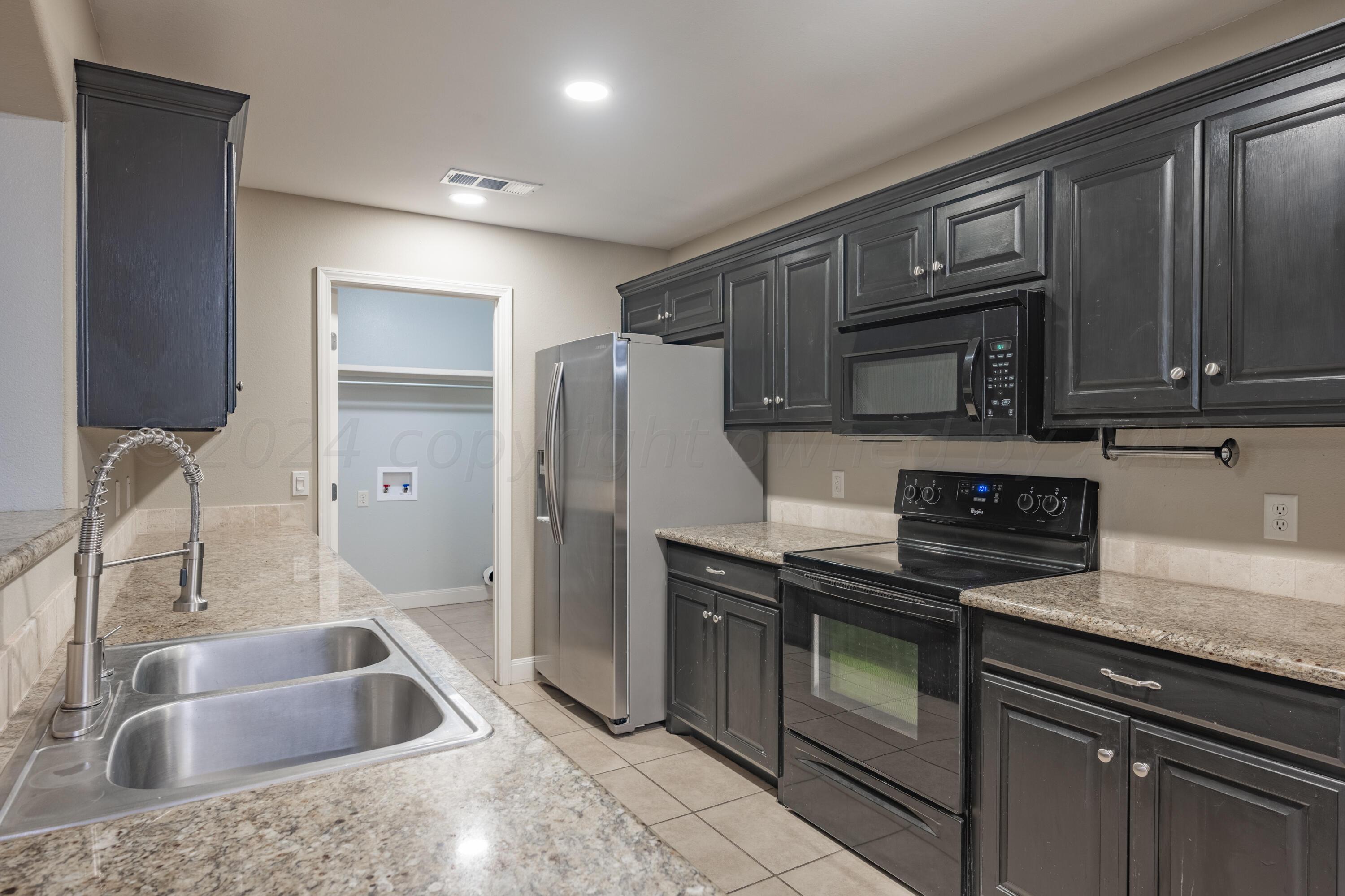 4512 Ross Street Amarillo, TX 79118 - Photo 3 of 24 a kitchen with granite countertop a sink stove and refrigerator