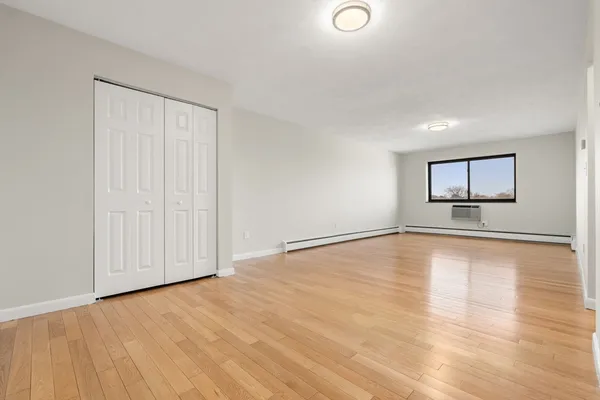 a view of empty room with wooden floor and fan