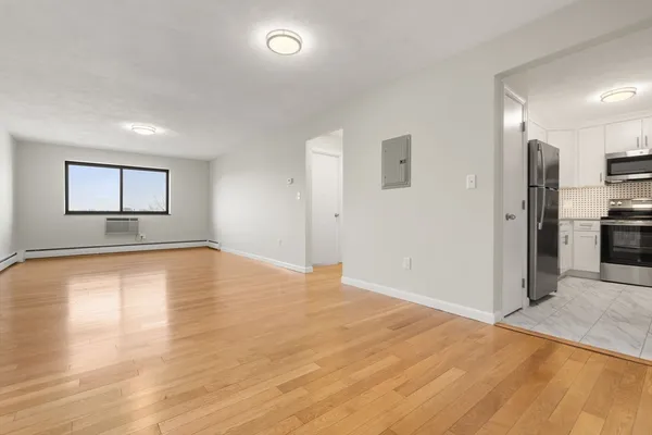 a view of empty room with wooden floor and window