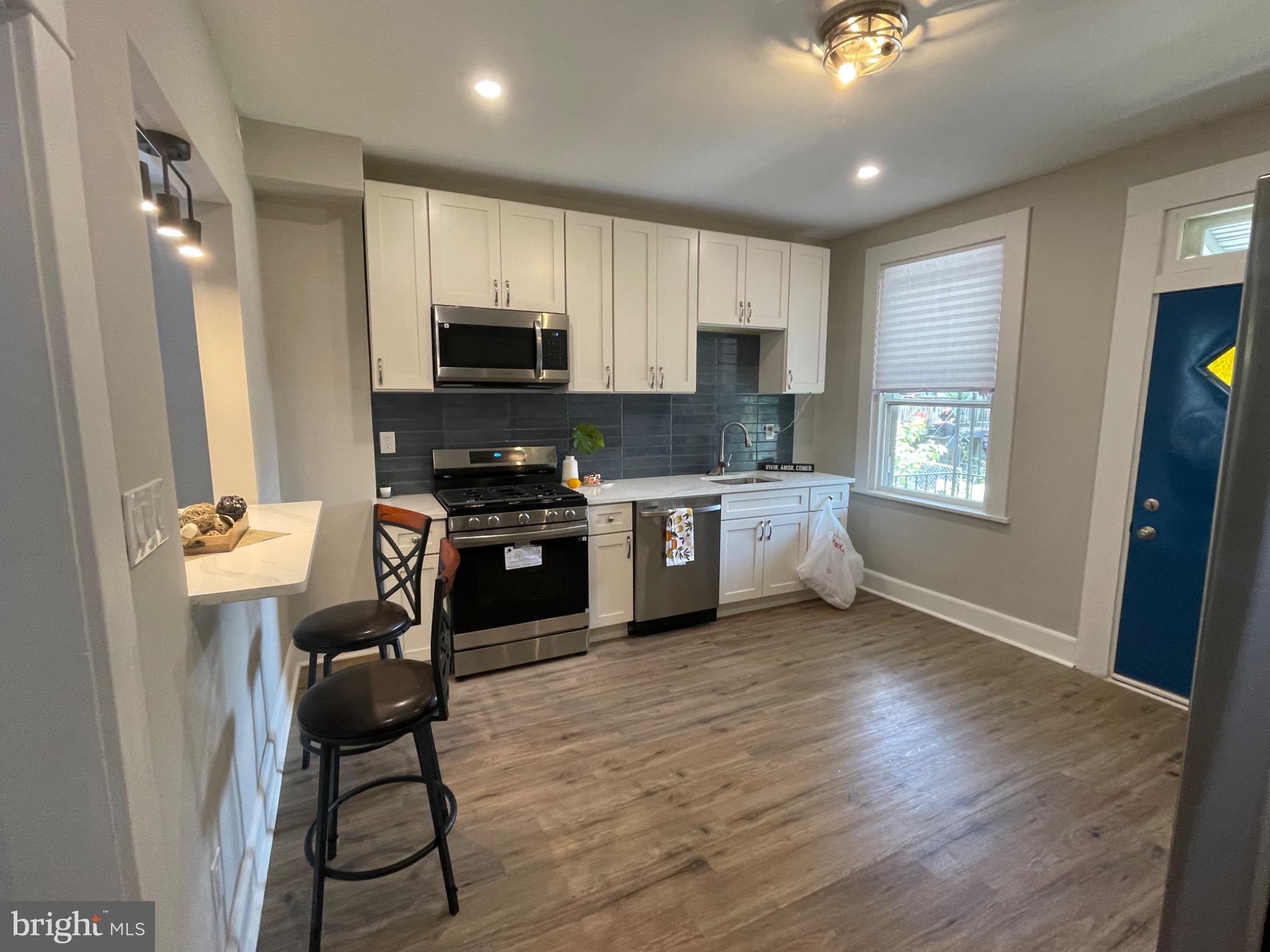 2301 Mosher Street Baltimore, MD 21216 - Photo 2 of 30 a kitchen with a table chairs refrigerator and microwave