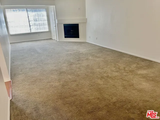 an empty room with windows and fireplace