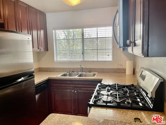 a kitchen with sink a stove and wooden cabinets