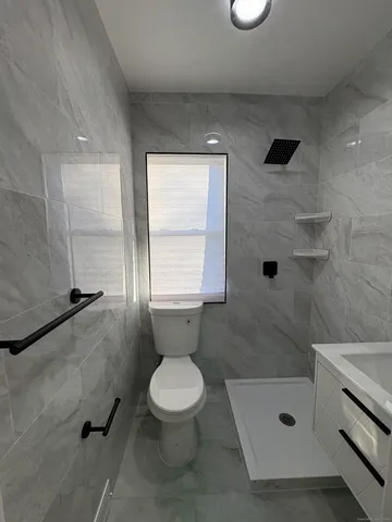 a bathroom with a shower a toilet and a window