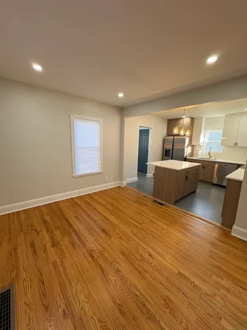 a view of kitchen and empty room with wooden floor