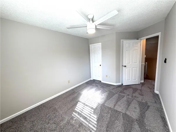 an empty room with closet and a ceiling fan