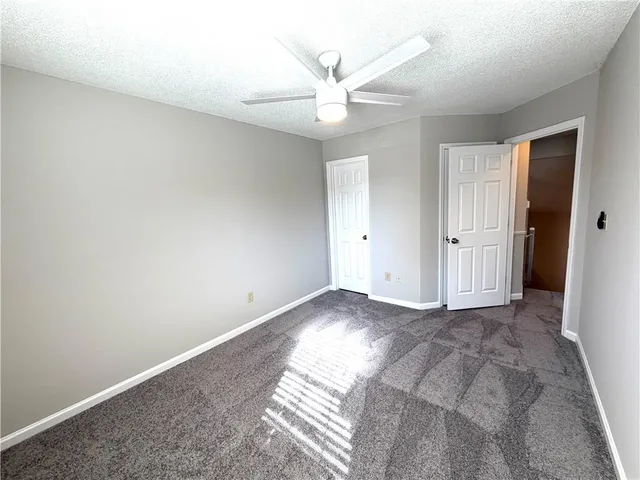 an empty room with closet and a ceiling fan