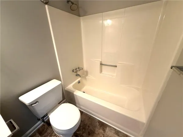 a white toilet sitting next to a bath tub
