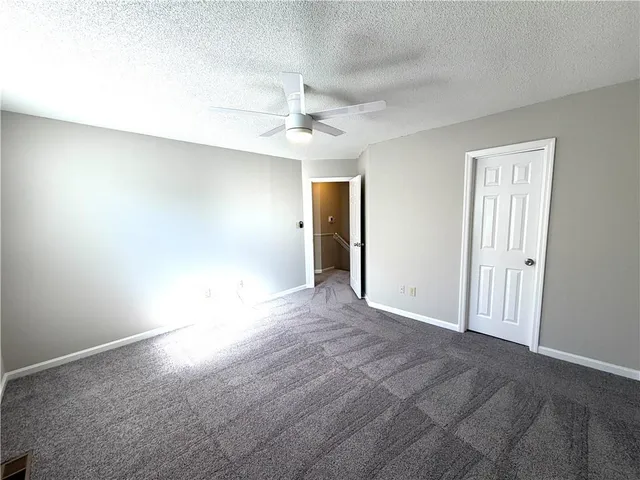 en empty room with windows and ceiling fan