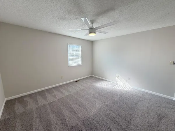 an empty room with a window and ceiling fan