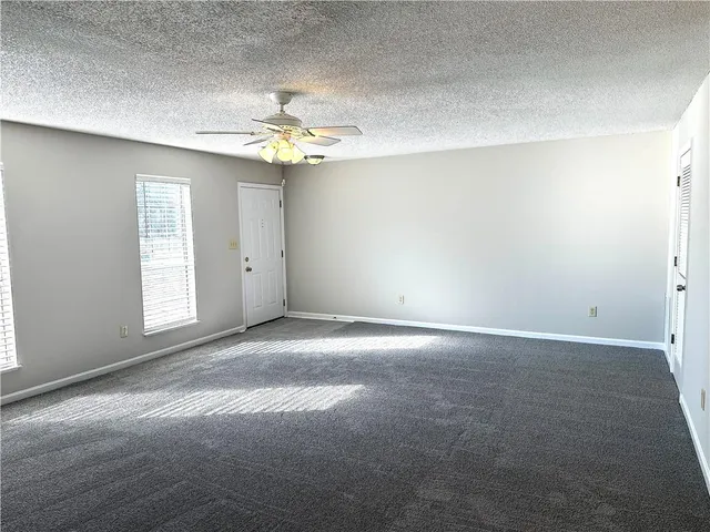 an empty room with windows and chandelier fan
