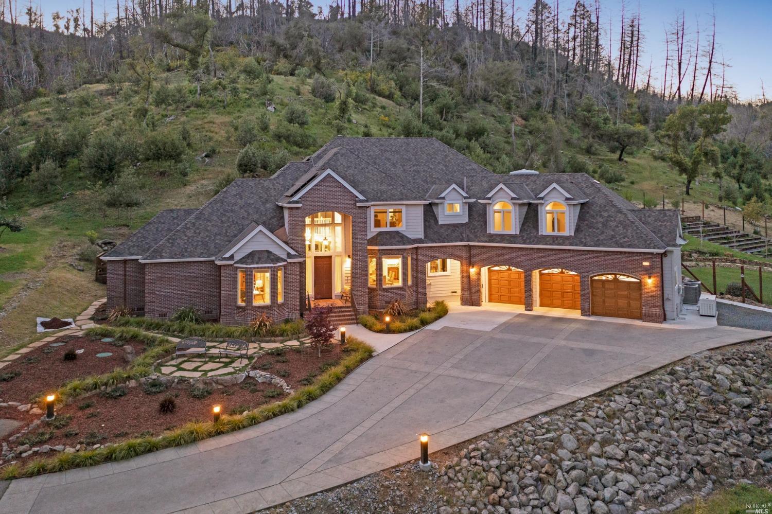 a front view of a house with a yard and large tree