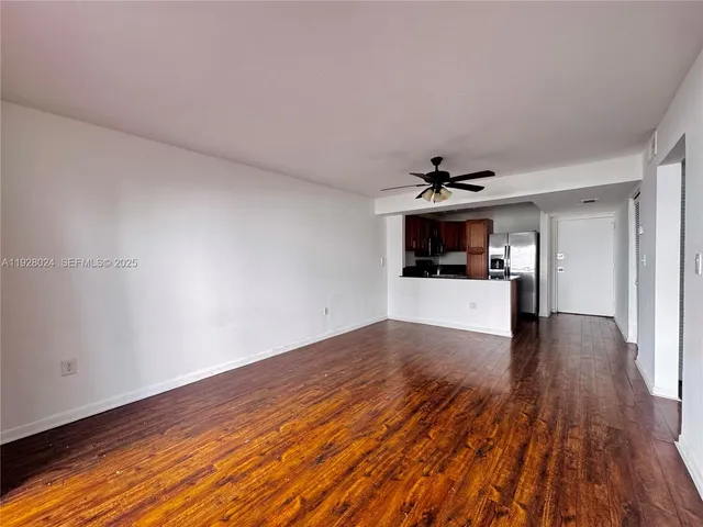 a view of a livingroom with wooden floor and kitchen space