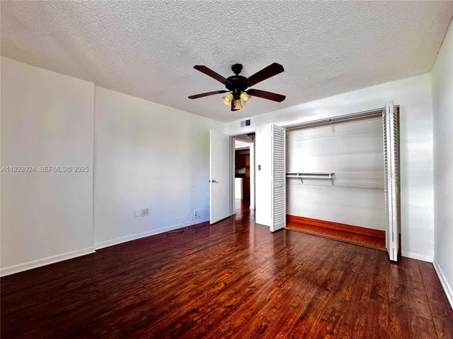a view of empty room with wooden floor and ceiling fan