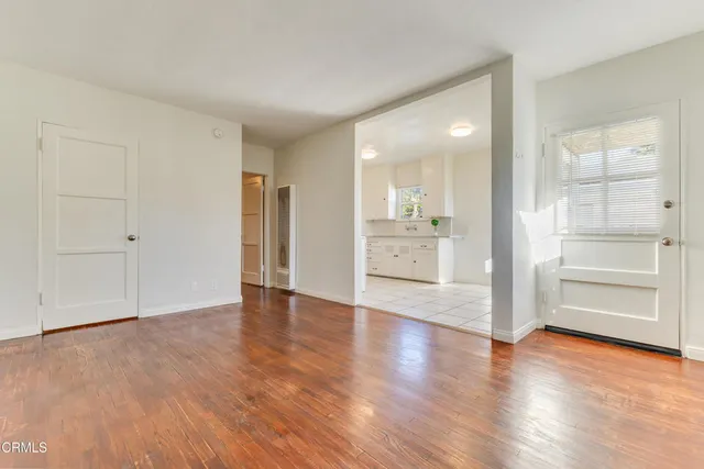 an empty room with wooden floor cabinet and windows