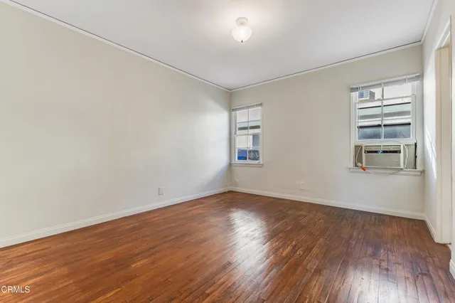 an empty room with wooden floor closet and windows