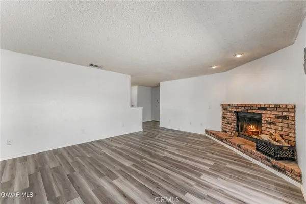a kitchen with stainless steel appliances a sink a stove a refrigerator with white cabinets and wooden floor