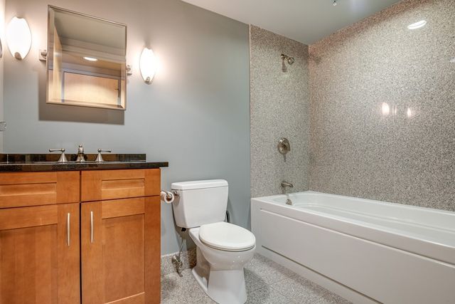 a bathroom with a granite countertop toilet sink and mirror