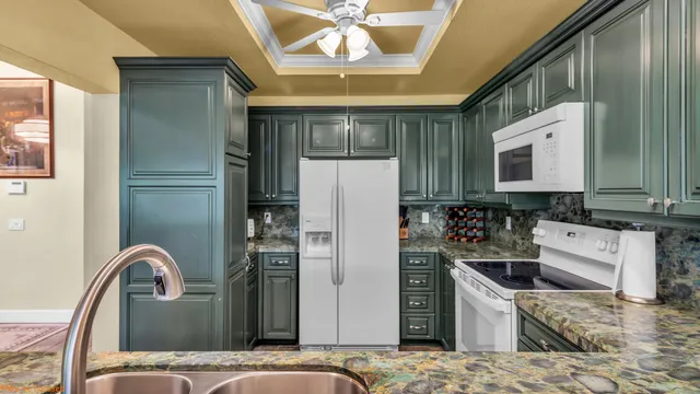 a kitchen with stainless steel appliances kitchen island granite countertop a refrigerator a stove and a sink with large countertops