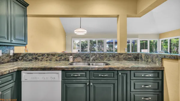 a kitchen with a granite countertop sink and a window