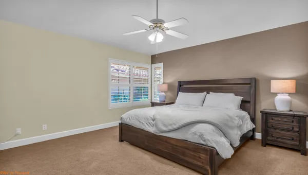 a large bed sitting in a bedroom next to a window and a chandelier