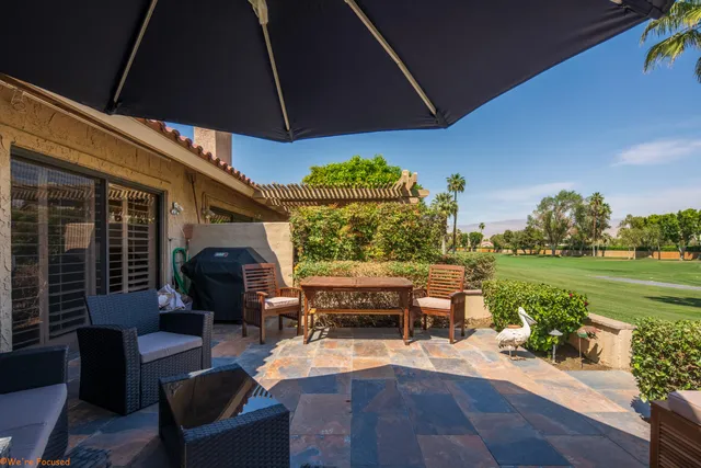 a view of a patio with couches table and chairs under an umbrella