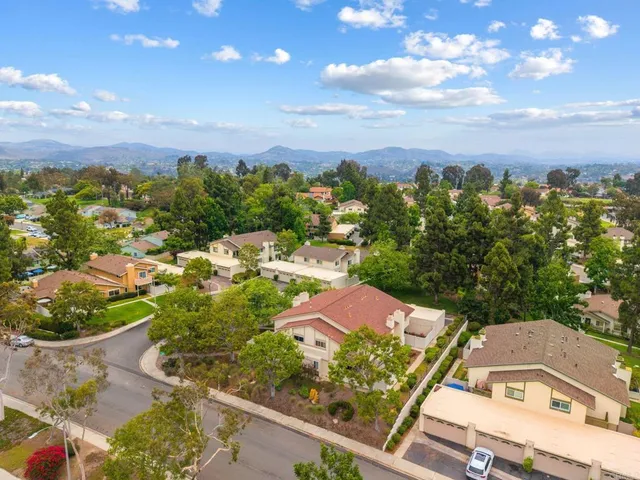 an aerial view of residential houses with outdoor space and trees