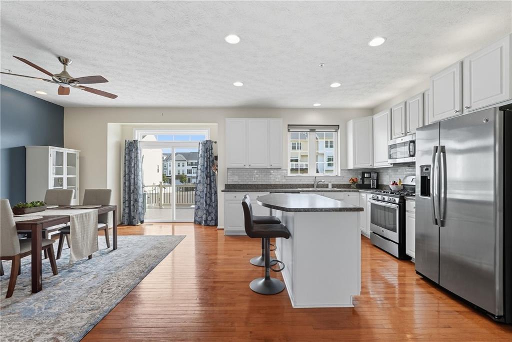 11 Truman Circle McKees Rocks, PA 15136 - Photo 9 of 33 a kitchen with stainless steel appliances granite countertop a refrigerator a stove top oven a sink dishwasher a dining table and chairs with wooden floor
