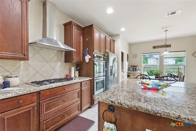 a kitchen with granite countertop lots of wooden cabinets stainless steel appliances and a counter space
