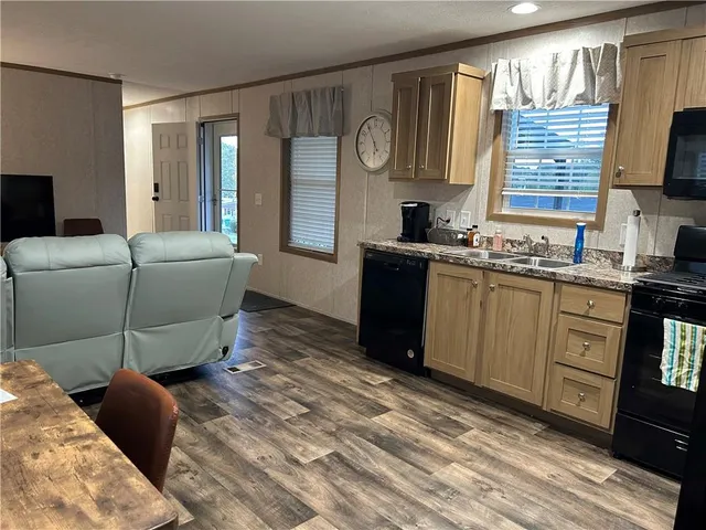 a living room with furniture a flat screen tv and kitchen view
