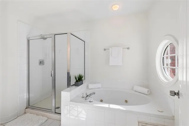 a bathroom with a tub a mirror and a shower
