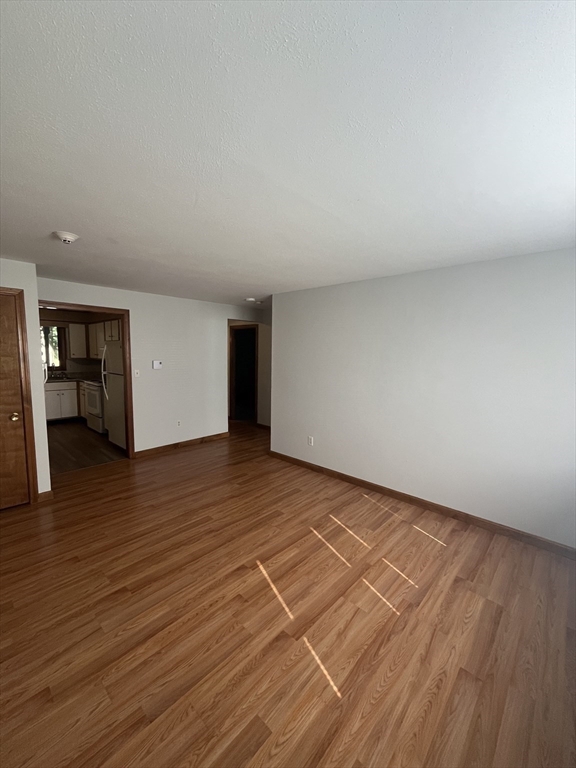35 School Street, Unit 7 Dracut, MA 01826 - Photo 7 of 22 a view of an empty room with wooden floor and a window