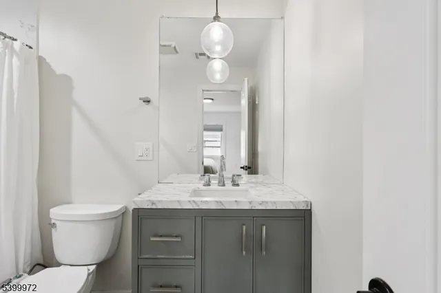 a bathroom with a granite countertop sink a toilet and a mirror