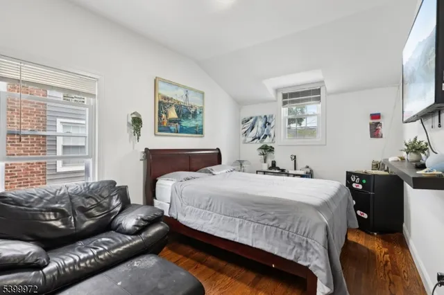 a bedroom with a bed couch and windows