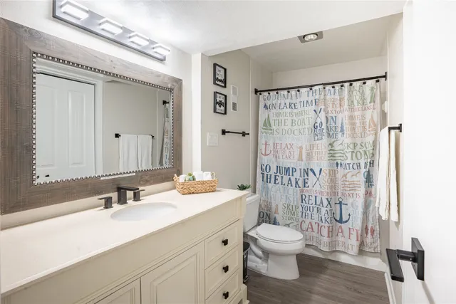 a bathroom with a double vanity sink toilet mirror and shower
