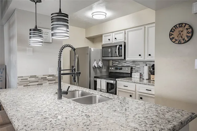 a kitchen with stainless steel appliances granite countertop a sink stove and refrigerator