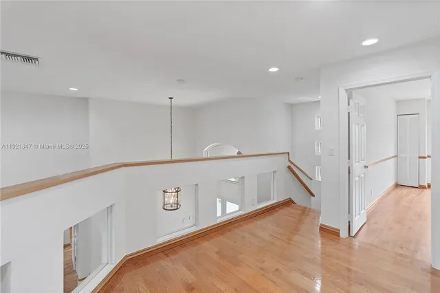 an empty room with wooden floor closet and windows
