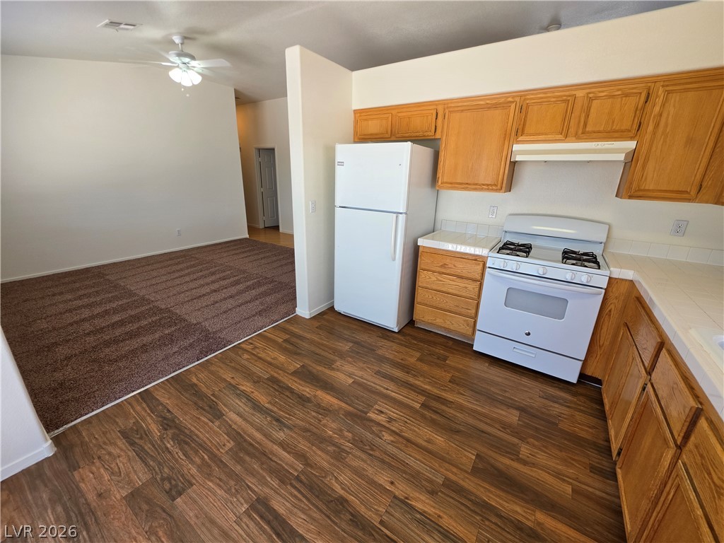 1154 Point Success Avenue Henderson, NV 89014 - Photo 3 of 26 A functional kitchen provides ample storage and essential appliances, flowing into a comfortable living space with plush carpeting.