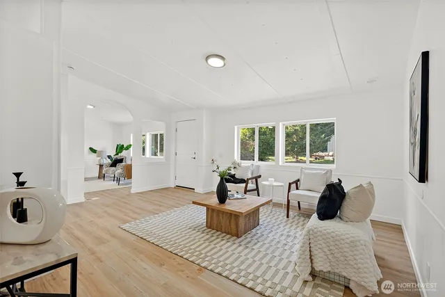a very nice looking dining room with kitchen island white cabinets wooden floor and a refrigerator