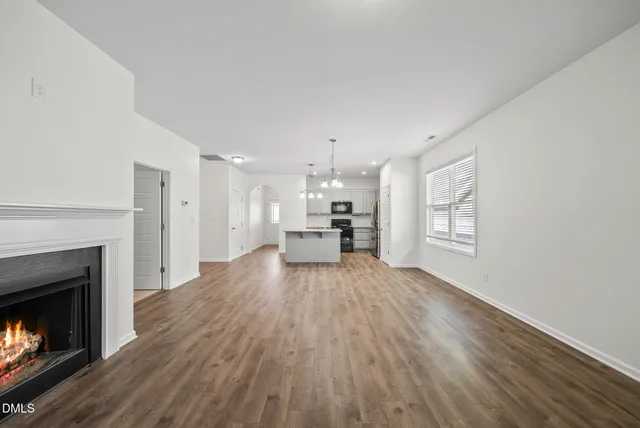 a view of empty room with wooden floor and fireplace