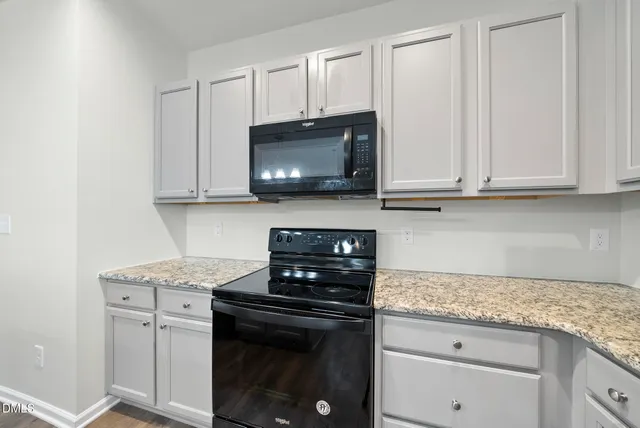 a kitchen with granite countertop stainless steel appliances a sink stove and wooden floor