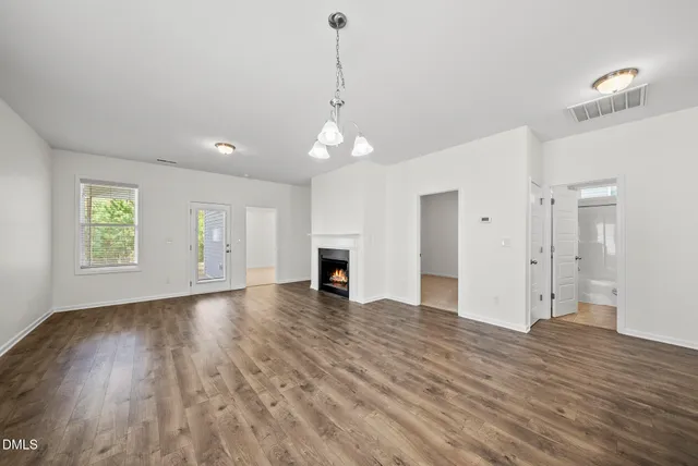 an empty room with wooden floor fireplace and windows