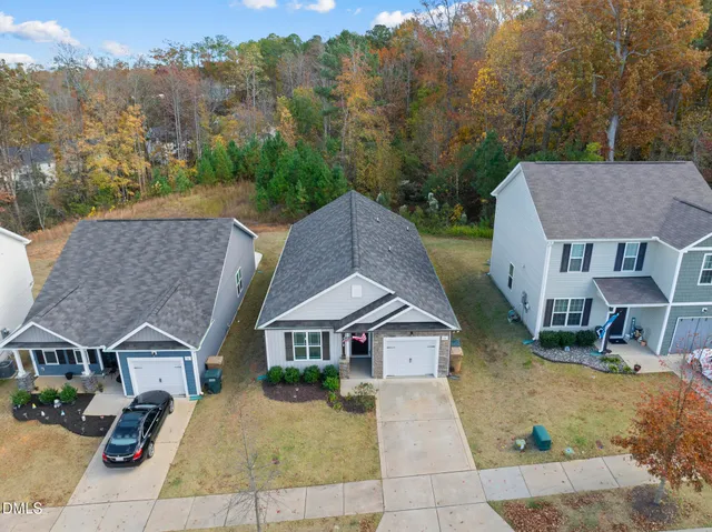 a view of a house with a yard plants and large tree