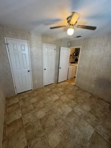 a view of a livingroom with a chandelier fan and kitchen view