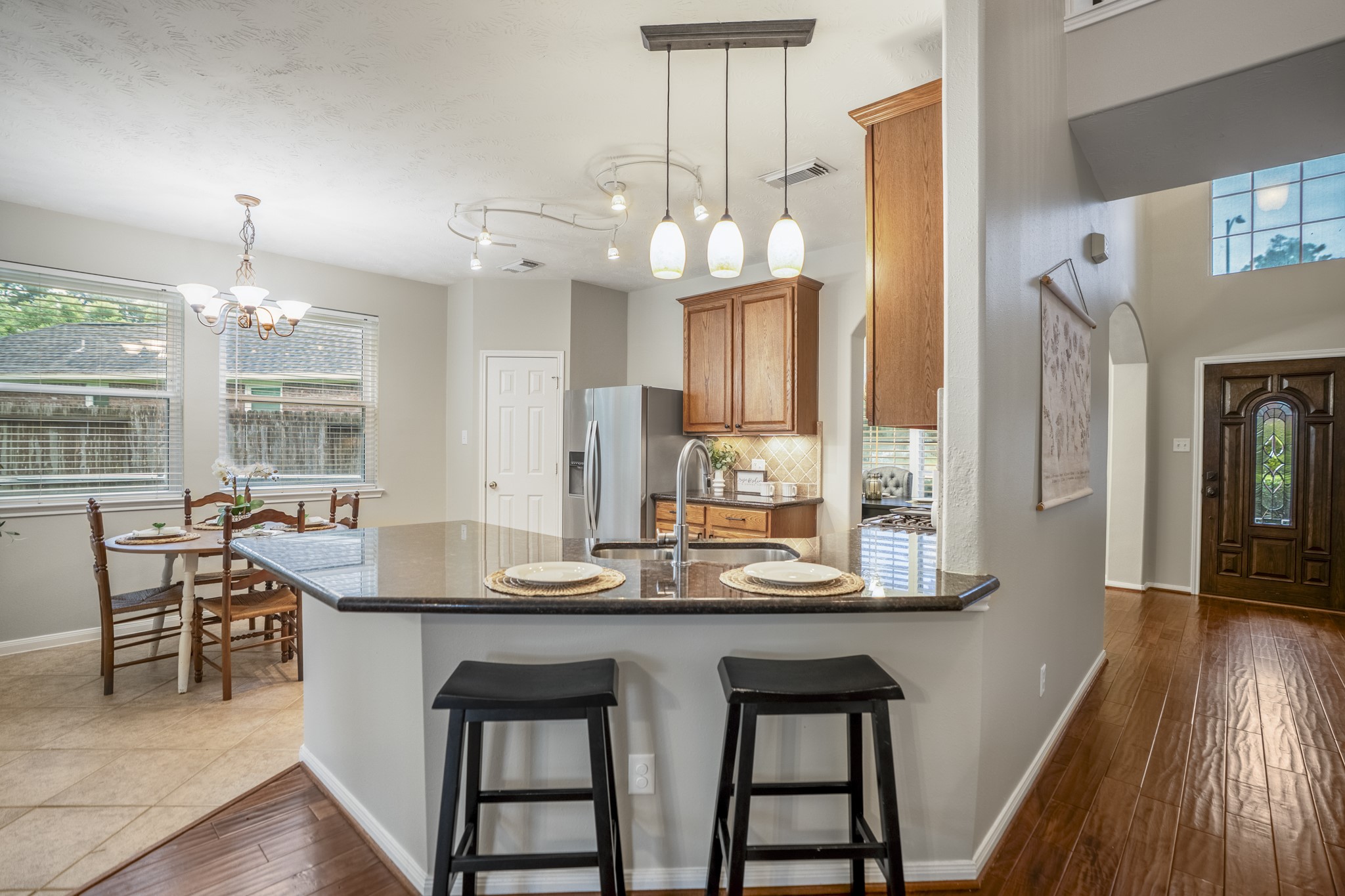 6311 Sparrows Glen Lane Spring, TX 77379 - Photo 12 of 50 At the kitchen bar, the main level starts to feel easy and connected—pendant lighting over the sink, breakfast space just to the side, and a clear view back toward the front entry for a layout that keeps everything within reach.