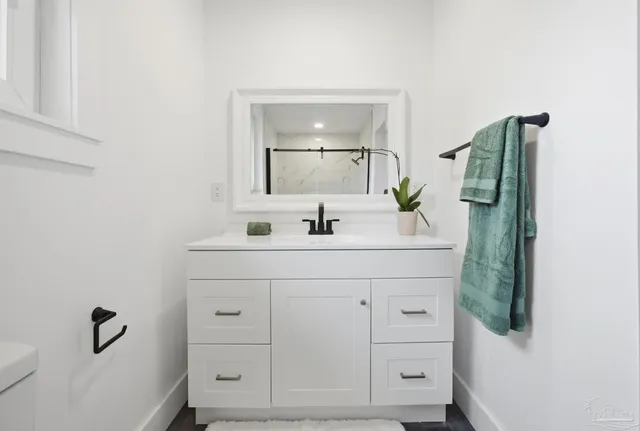 a bathroom with a granite countertop toilet a sink and a mirror