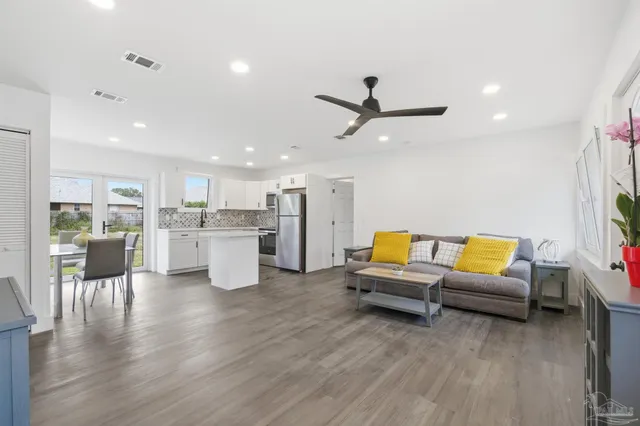a living room with furniture and kitchen view with wooden floor